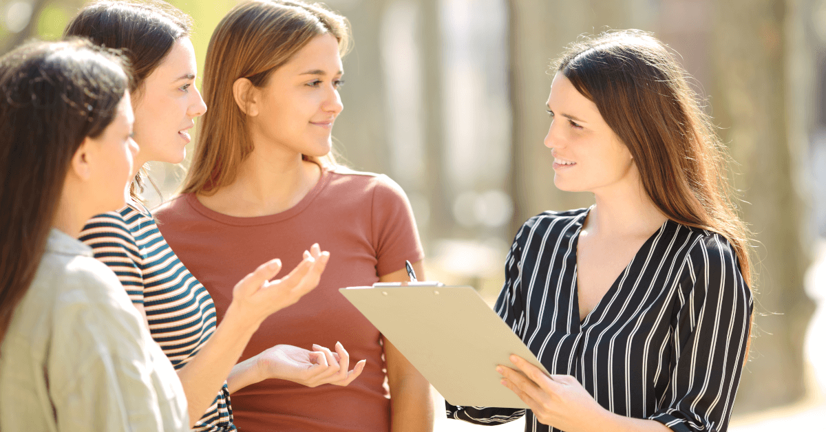 A woman giving a survey to three other women.