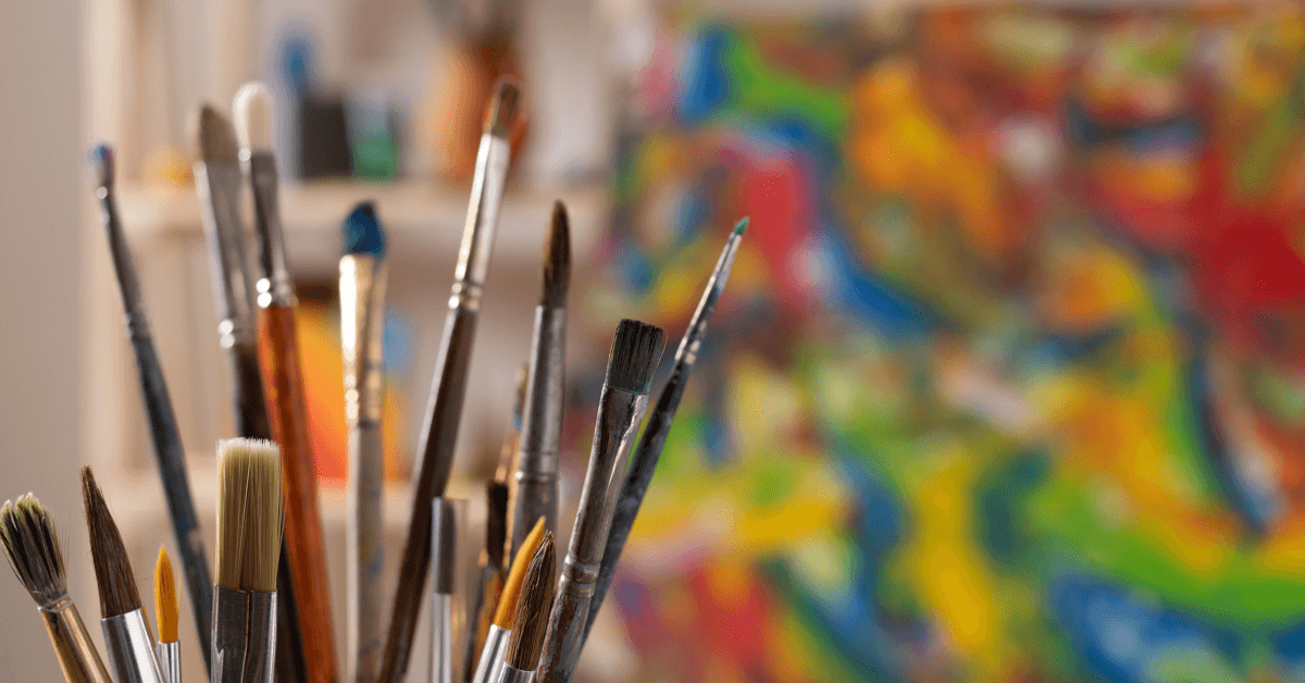 Paintbrushes next to an artist's canvas.