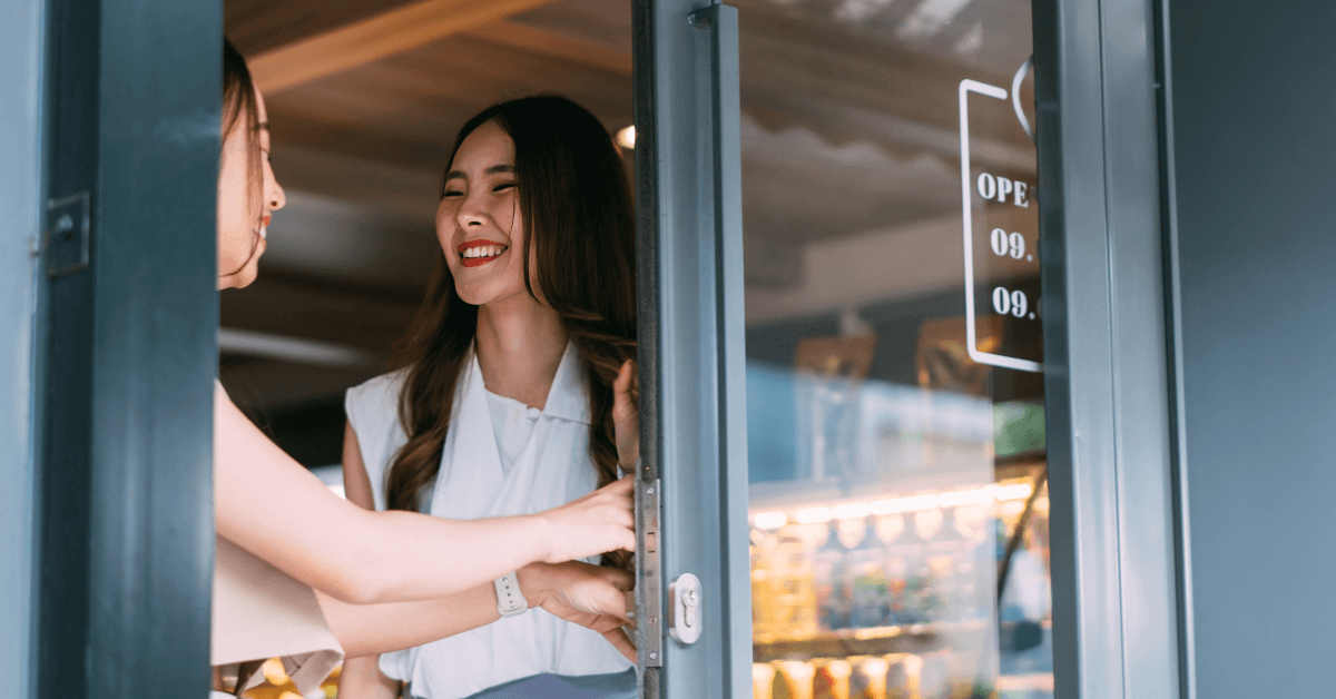 A customer walking through a door while speaking with a shopkeeper.