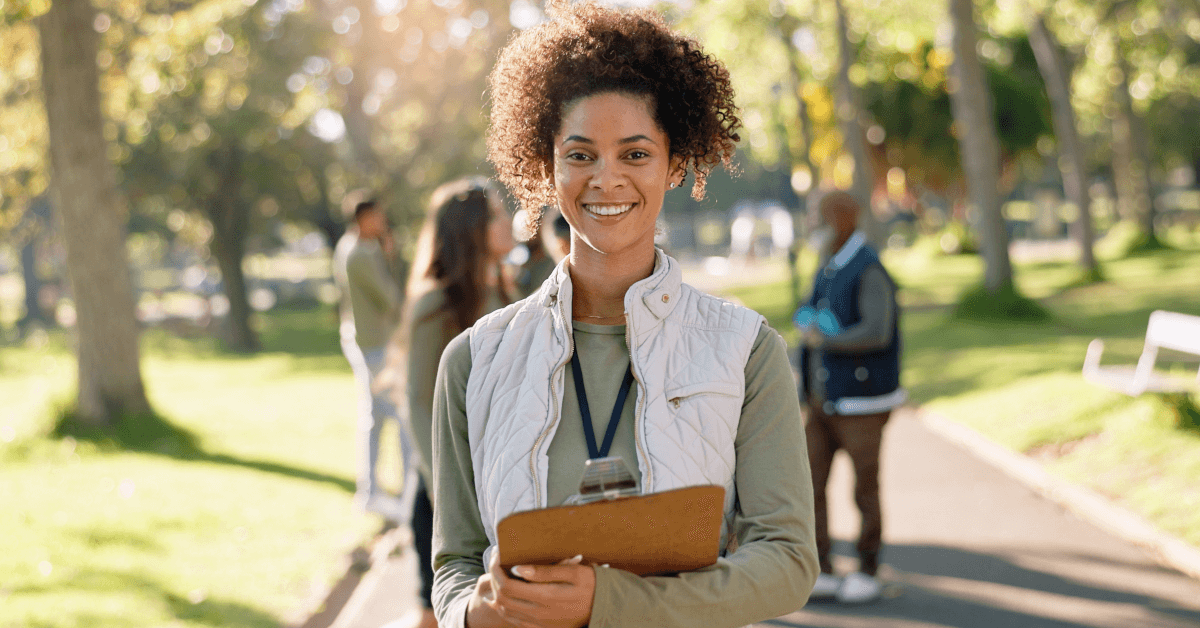 A smiling woman holding a survey clipboard.