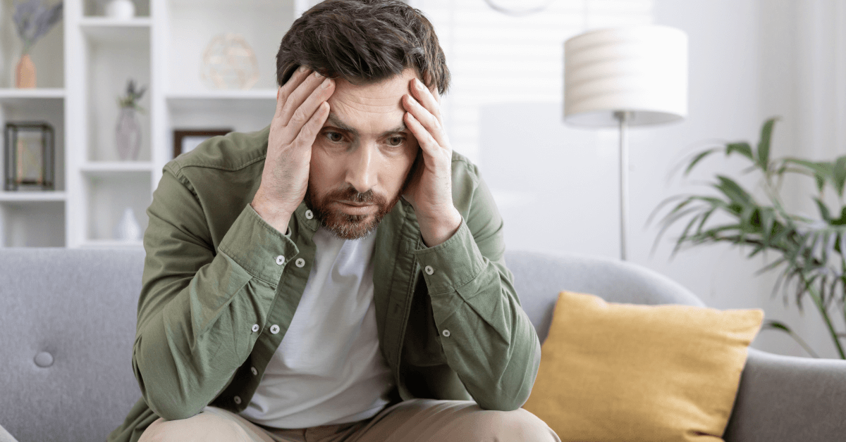 A man with head in hands looking frustrated.