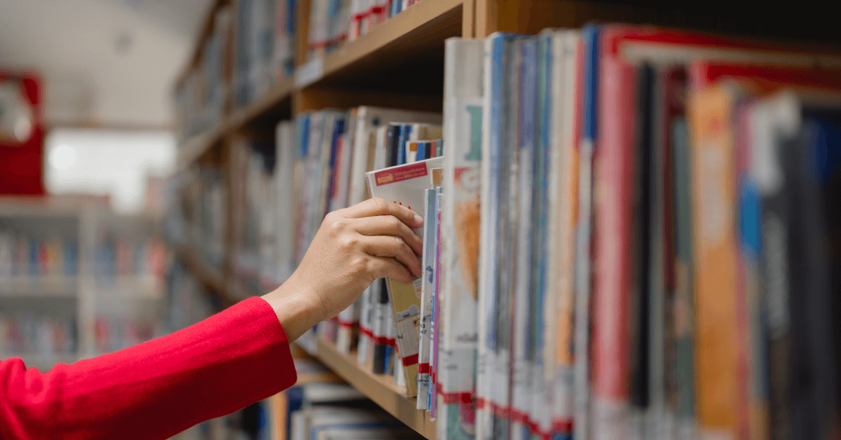 Selecting a book off a library shelf.